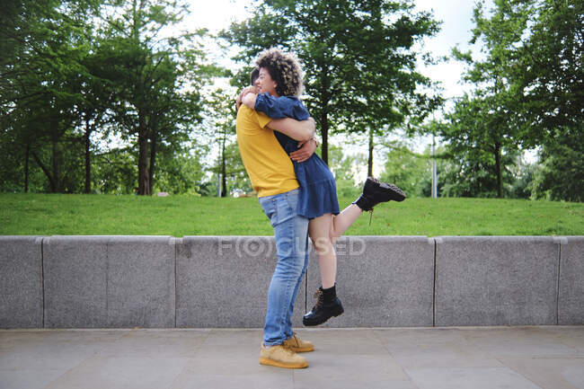 Giovane uomo sollevamento fidanzata mentre abbraccia al parco — Foto stock