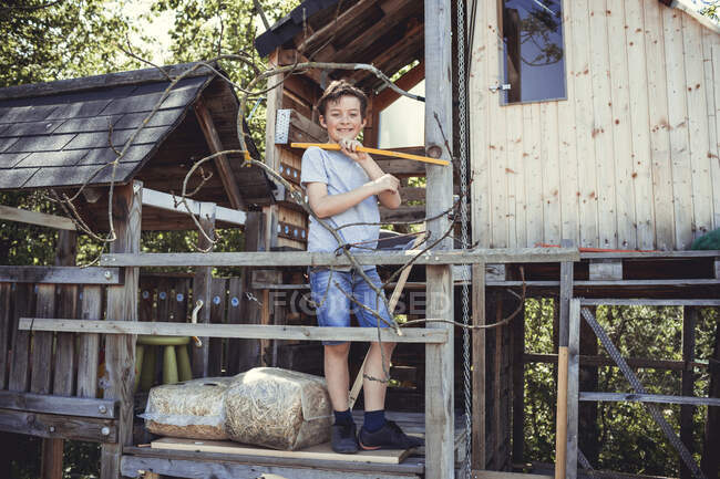 Усміхнений хлопчик тримає робочий інструмент в дерев'яному кріслі кролика — стокове фото