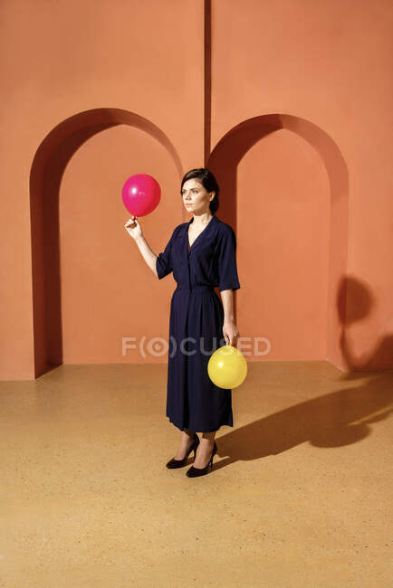 Женщина держит воздушные шары перед стеной с арками — стоковое фото