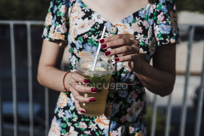 Giovane donna che tiene monouso tazza di bevanda — Foto stock