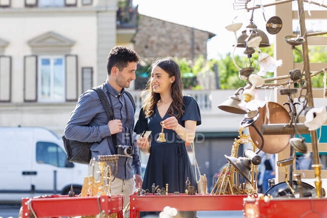 Smiling woman holding bell and credit card while standing by man at street market — Stock Photo
