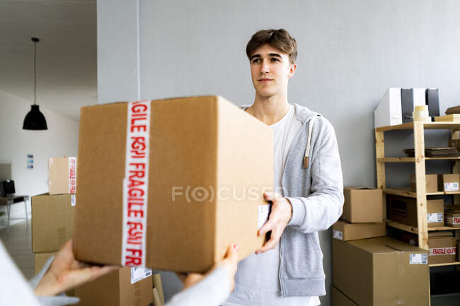 Geschäftsmann liefert Paket an Kundin im Lager aus — Stockfoto