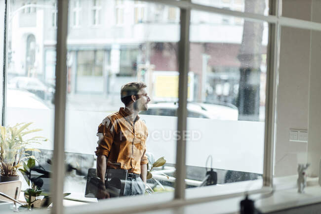 Mature businessman with digital tablet and hand in pocket standing by window — Stock Photo