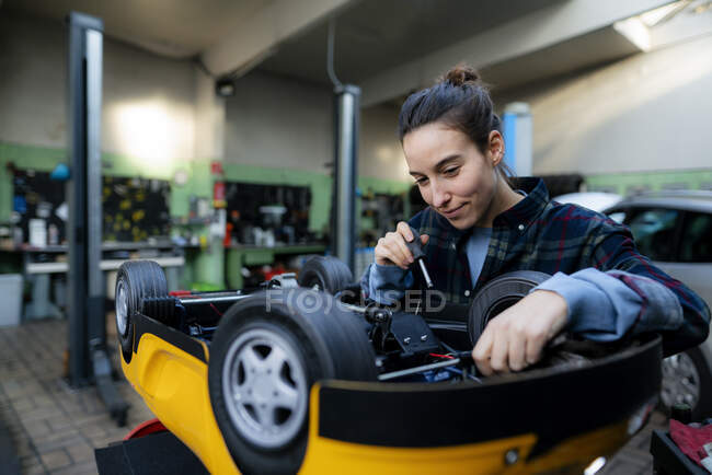 Mechanikerin repariert Spielzeugauto in Werkstatt — Stockfoto