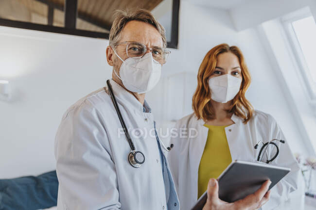 Чоловік - лікар з цифровою табличкою, що стоїть біля співробітника лікарні. — стокове фото