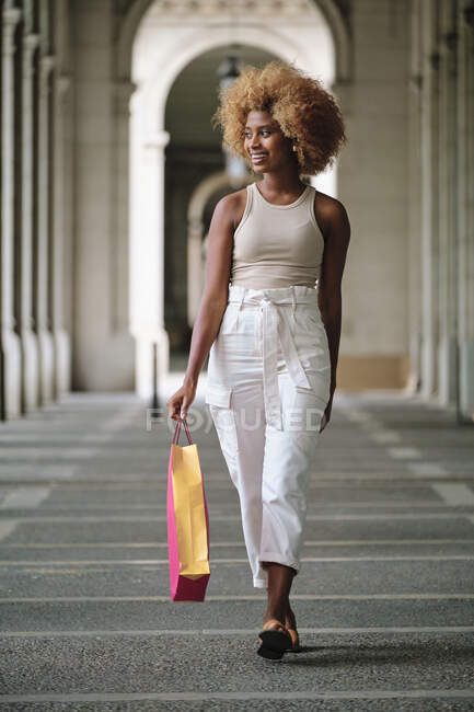 Lächelnde Frau mit Einkaufstasche läuft auf Gehweg — Stockfoto