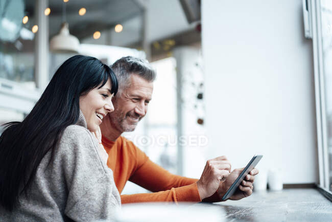 Улыбающаяся взрослая пара с помощью смартфона в кафе — стоковое фото