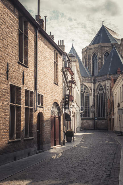 Bélgica, Flandes Occidental, Brujas, Callejón de adoquines con la Catedral de San Salvador de fondo - foto de stock
