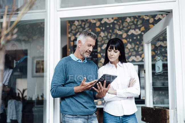 Male entrepreneur with digital tablet explaining to colleague at cafe — Stock Photo