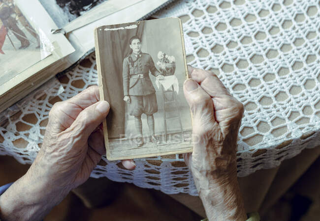 Femme âgée se rappelant passé tout en regardant vieille photographie à la maison — Photo de stock