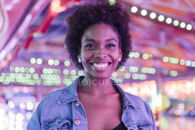 Mulher sorridente no parque de diversões iluminado — Fotografia de Stock