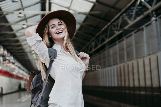 Весела блондинка у рюкзаку на залізничній станції. — стокове фото
