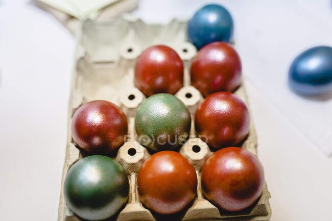 Multi colored Easter eggs in tray on table at home — Stock Photo