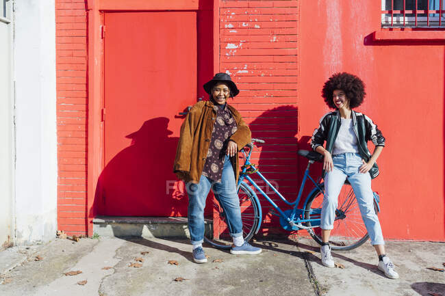 Giovani amici sorridenti mentre si appoggiano sulla bicicletta — Foto stock