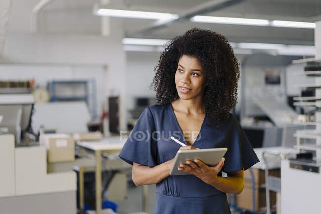 Afro-Profi schaut weg, während er digitales Tablet im Büro hält — Stockfoto