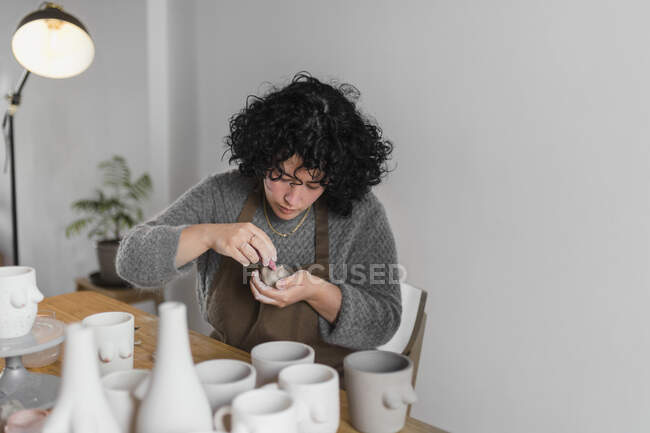 Artesana mujer pintando producto de arte mientras trabaja en el taller - foto de stock