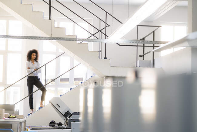 Зайнята жінка зі схрещеними руками, стоячи на сходинках у промисловості. — стокове фото