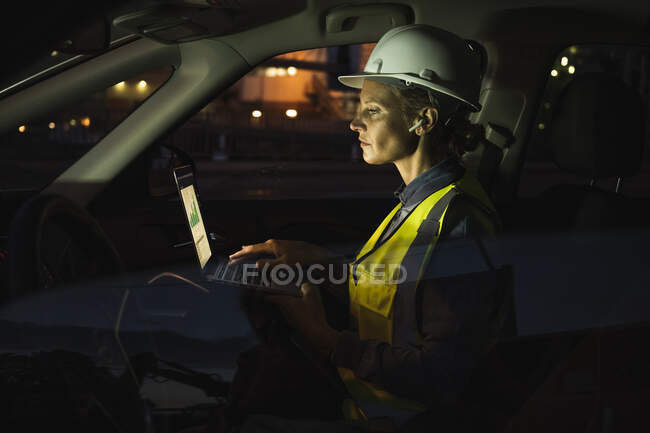 Профессиональная женщина с ноутбуком в машине ночью — стоковое фото