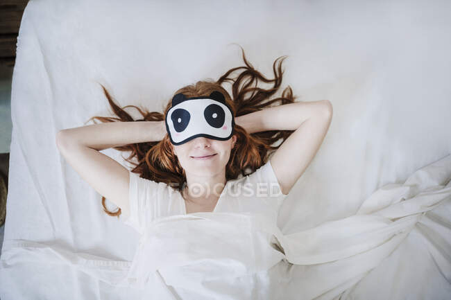 Donna rilassata con le mani dietro la testa che dorme sul letto — Foto stock