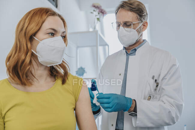 Male doctor preparing patient for COVID-19 vaccination in examination room — Stock Photo