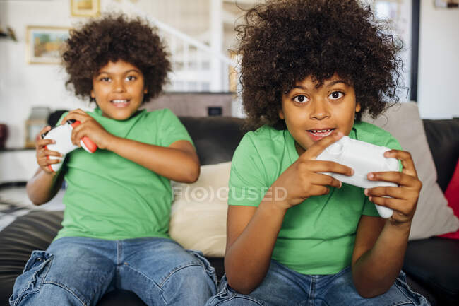 Frères jumeaux concentrés jouant à un jeu vidéo à la maison — Photo de stock
