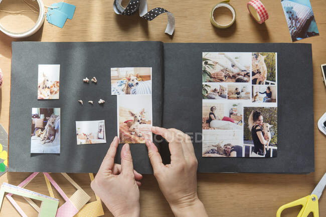 Mujer haciendo álbum de recortes de perro mascota en la mesa - foto de stock