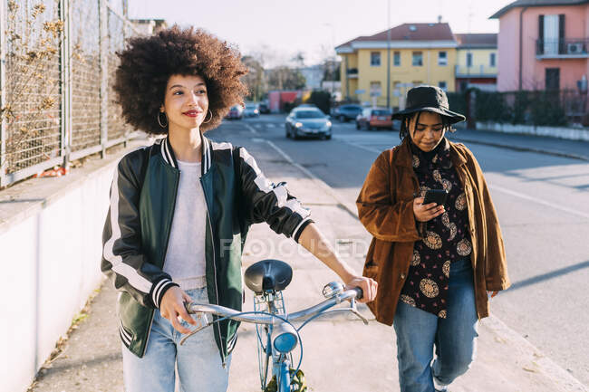 Молодая женщина, идущая на велосипеде с подругой по тропинке — стоковое фото