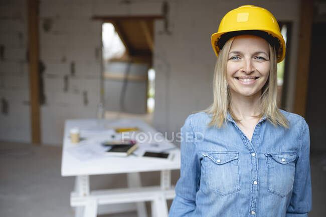 Улыбающаяся женщина-подрядчик в каске на стройке — стоковое фото