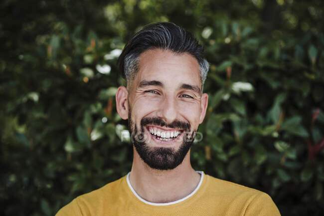 Homem barbudo sorrindo na frente das plantas — Fotografia de Stock