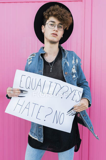Гей чоловік питає про рівність, що стоїть перед рожевою стіною — стокове фото