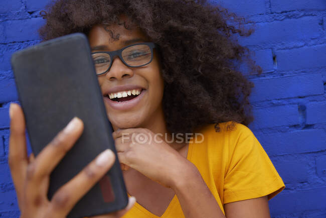 Femme souriante prenant selfie par téléphone portable devant un mur de briques — Photo de stock