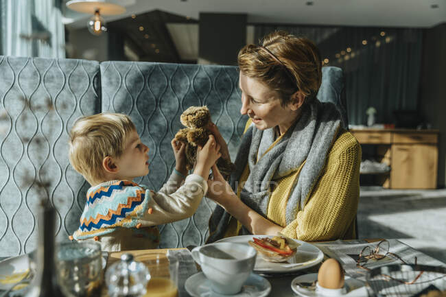 Мати і син грають з іграшковою твариною, сидячи за столом в готелі — стокове фото