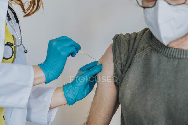 Medico che somministra il vaccino COVID-19 nel braccio del paziente nella sala d'esame — Foto stock