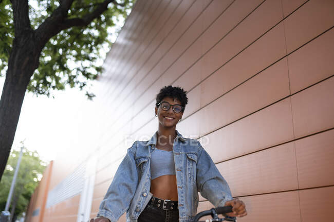 Молода жінка у джинсовому піджаку біля стіни. — стокове фото