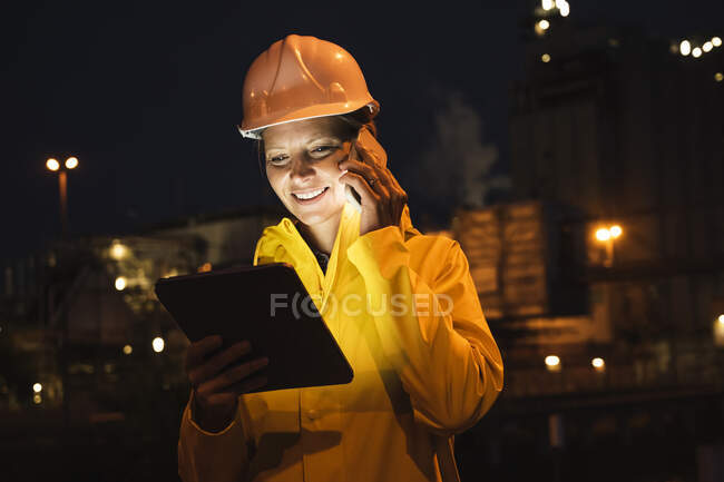 Lächelnde Berufstätige sprechen auf dem Smartphone und halten nachts ein digitales Tablet in der Hand — Stockfoto
