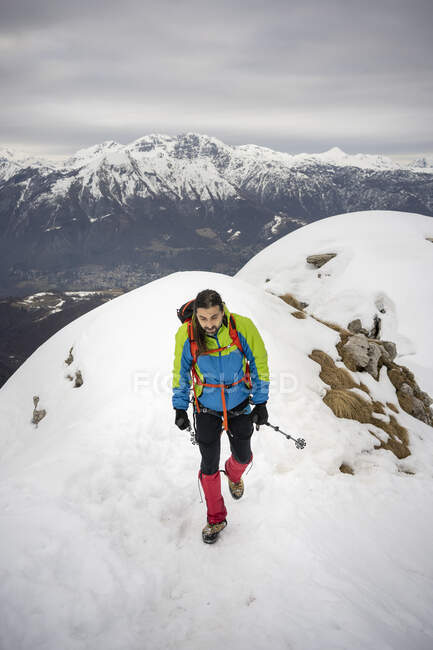 Alpinist walking with hiking pole on snowcapped mountain — Stock Photo