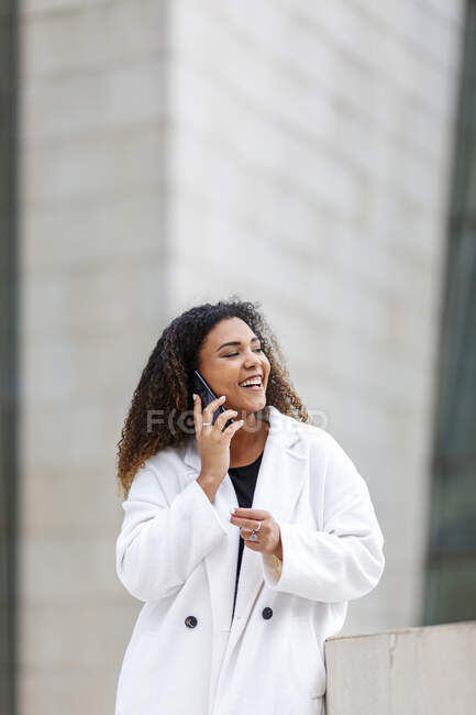 Mujer joven riendo mientras habla por teléfono inteligente - foto de stock