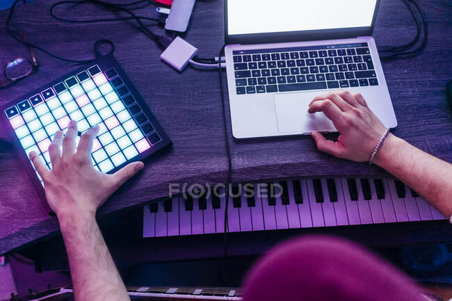 Homme utilisant une tablette numérique et un ordinateur portable tout en composant de la musique au studio — Photo de stock