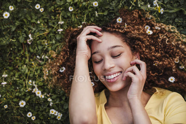 Sorridente giovane donna con gli occhi chiusi sdraiata sul prato — Foto stock