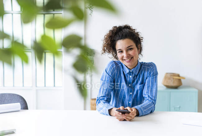 Female entrepreneur smiling while sitting by desk in office — Stock Photo