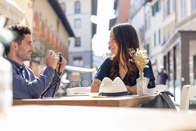 Männlicher Tourist fotografiert Frau vor Bürgersteig-Café durch Kamera — Stockfoto