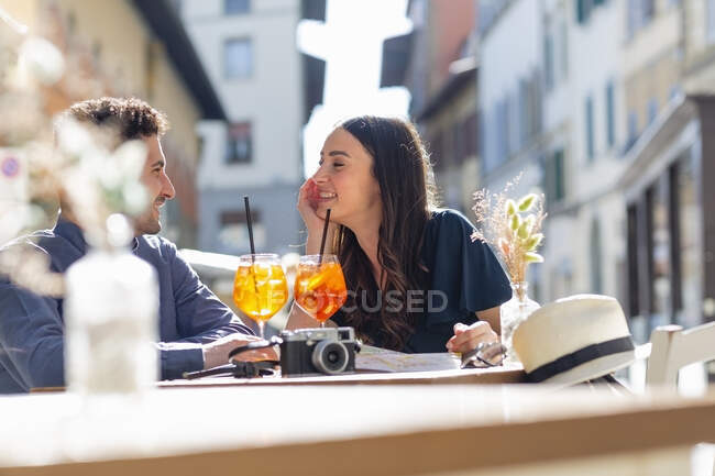 Pareja con bebidas hablando mientras está sentado en el café de la acera - foto de stock