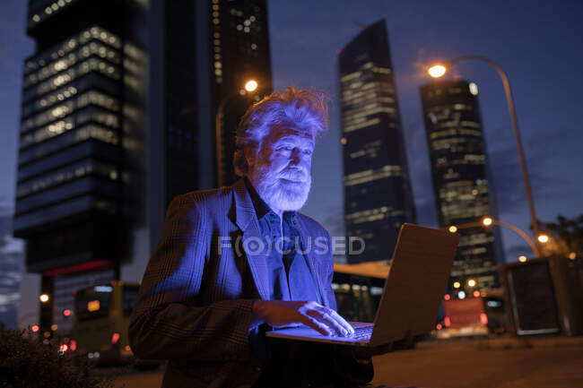Professionista maschio utilizzando il computer portatile in città di notte — Foto stock