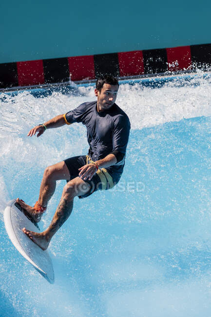 Atleta di sesso maschile che pratica surf con tavola da surf in piscina — Foto stock