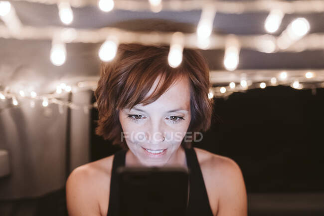 Donna sorridente utilizzando il telefono cellulare nel furgone illuminato di notte — Foto stock