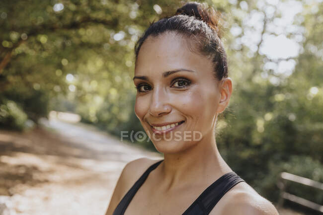 Sportswoman souriant tout en se tenant au parc — Photo de stock