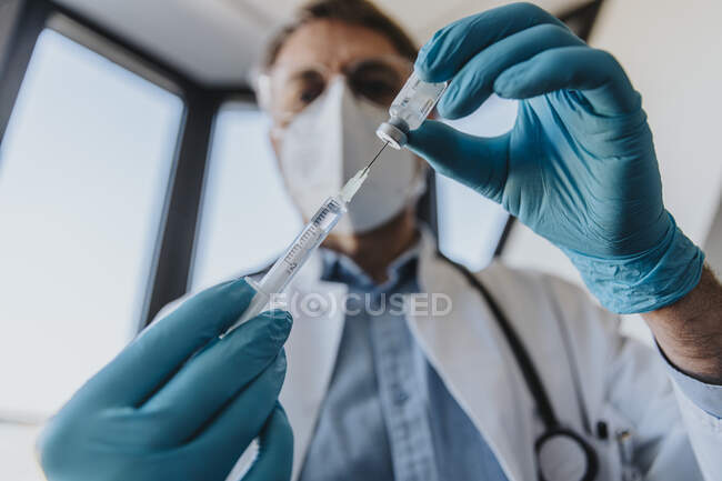 Siringa per iniezione da parte del medico maschio in flaconcino mentre si trova in clinica — Foto stock