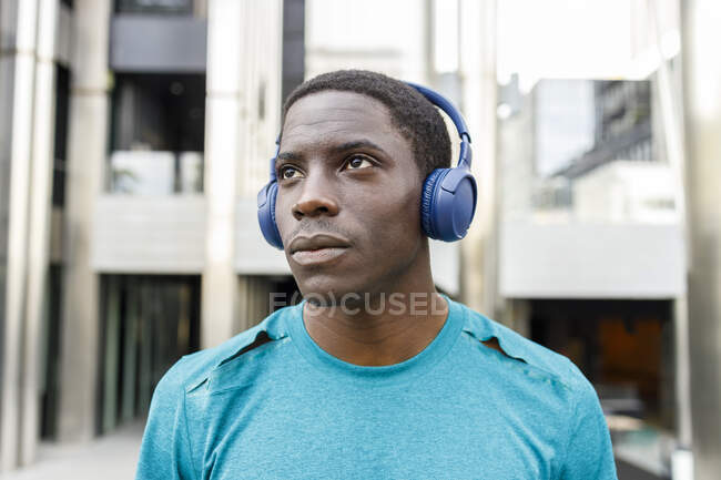 Африканський чоловік роздумував над тим, як слухати музику через навушники на вході до будівлі. — стокове фото