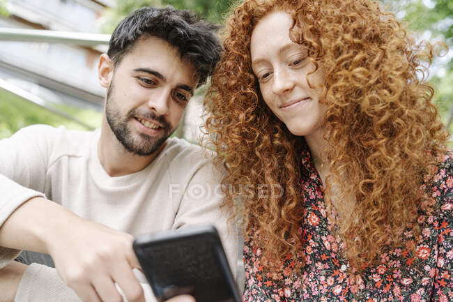 Giovane uomo con fidanzata utilizzando smart phone — Foto stock