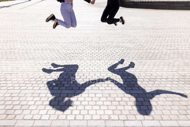Тіні друзів-жінок, які стрибають на стежку в сонячний день. — стокове фото